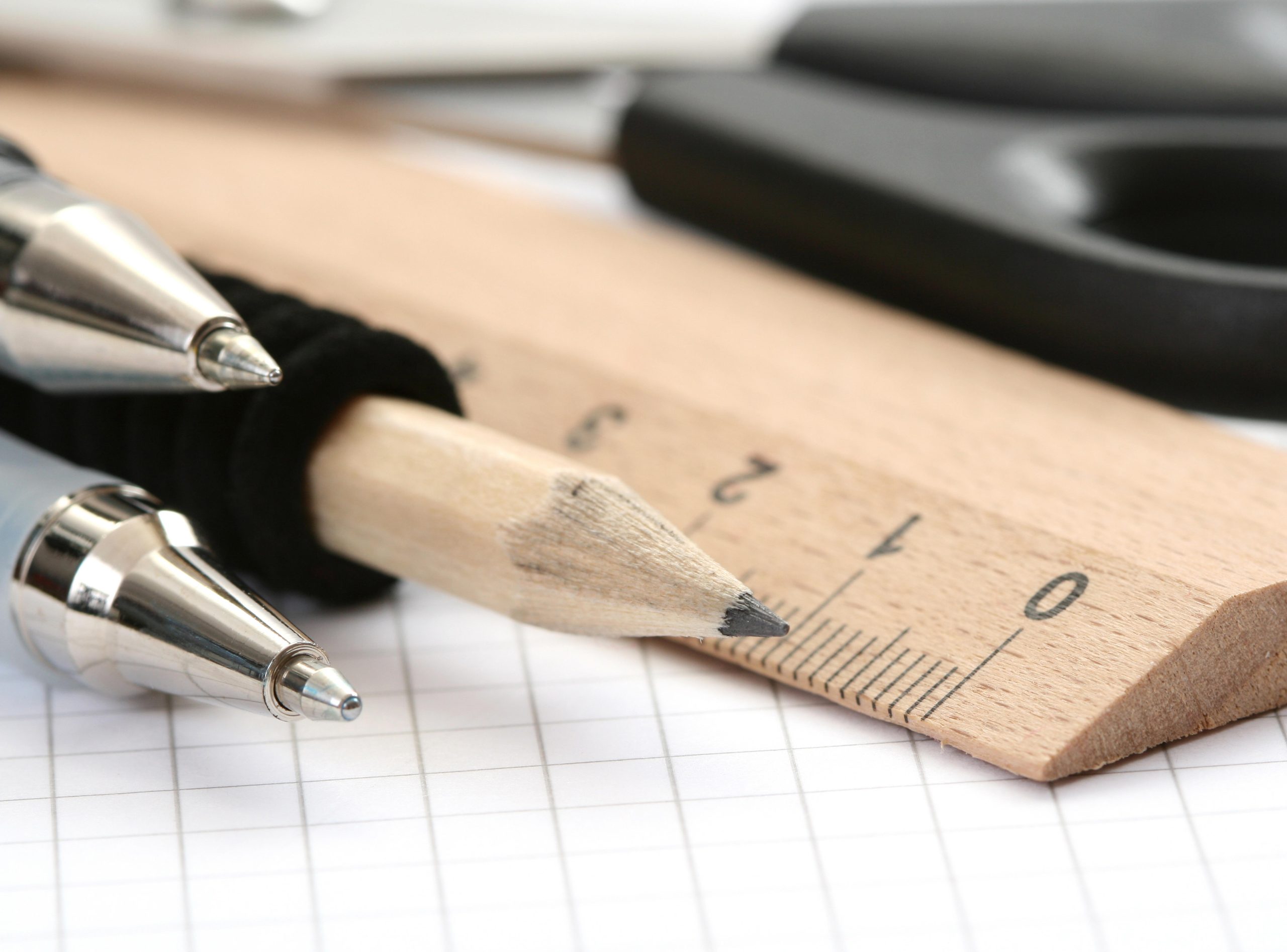 Drei Stifte und ein Lineal auf kariertem Papier